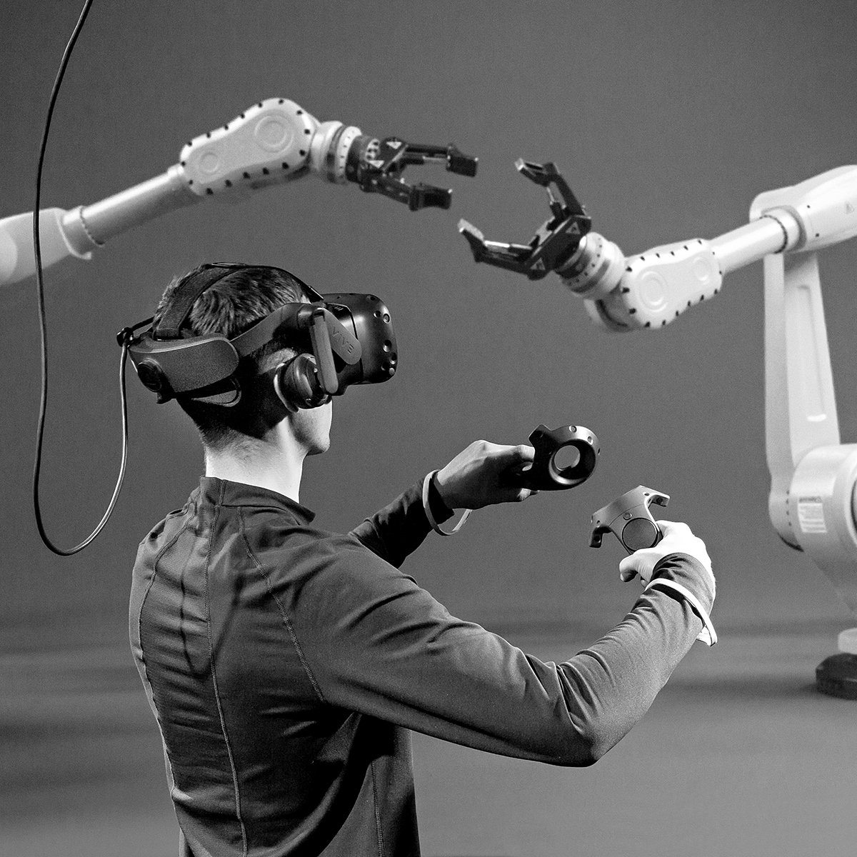 Schwarzweißfoto einer Person im Human Factors Lab von hinten, die mit einer VR-BRILLE Roboter-Arme bedient