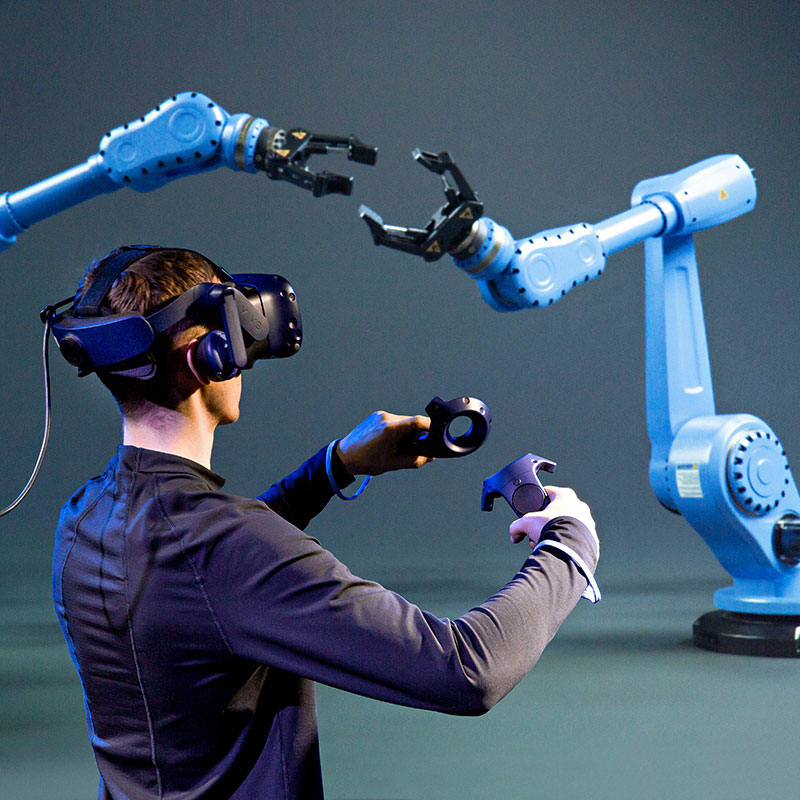 Person von Hinten mit VR-Brille steuert Roboter-Arme