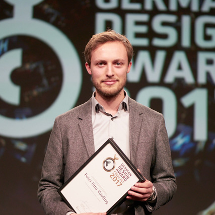 Student hat German Design Award bekommen und hält die Auszeichnung in der Hand.