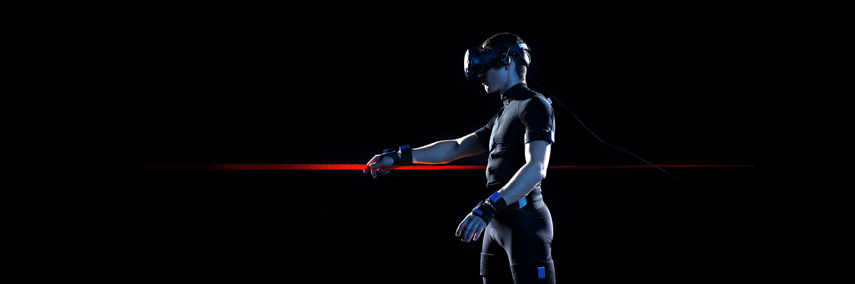 Eine Person die eine VR-Brille trägt und einen roten Lichtstrahl in der rechten Hand hält im Profil